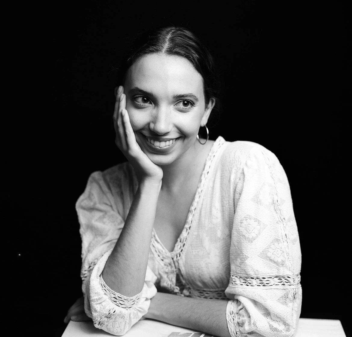 Lauren smiling in a black and white portrait with her chin resting on her hand